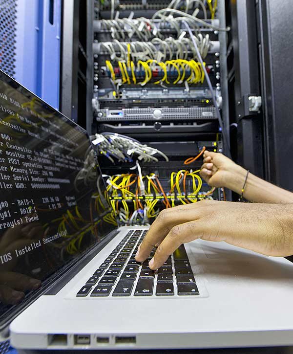 Technician running a server diagnostic on a laptop in front of an open server rack